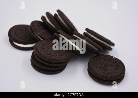 Schokoladenschwarzes dünnes Plätzchen mit weißer Füllung, köstlicher Milch-Oreo-Plätzchen auf weißem Hintergrund verstreut. Stockfoto