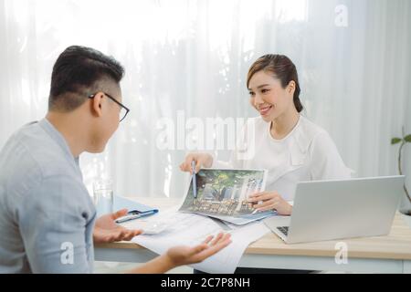 Immobilienmakler zeigt Hauspläne für Kunden im Büro. Stockfoto