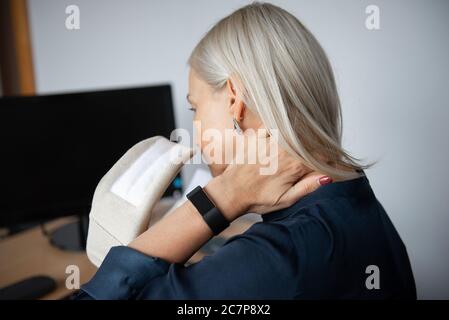 Reife Frau in Schmerzen trägt einen chirurgischen Kragen auf sie Hals, Arbeiten am Computer im Büro Stockfoto