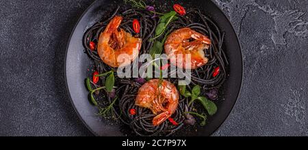 Italienische Pasta schwarze Spaghetti mit Garnelen und Microgreens, Draufsicht. Stockfoto
