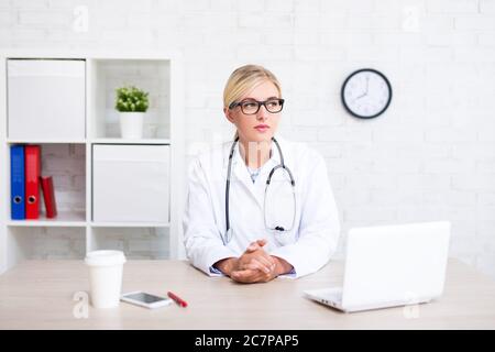 Porträt einer jungen Ärztin, die im Büro sitzt und an etwas denkt Stockfoto