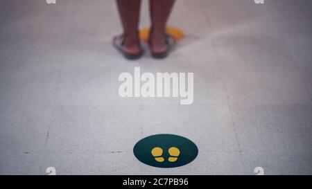 Stehen Sie hier Fußschild oder Symbol auf dem Boden mit den Menschen ist Kellner, Social Distancing Konzept. Stockfoto