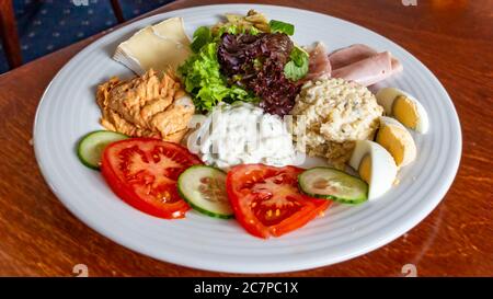 Gericht mit einer Kombination aus drei verschiedenen Salaten: Russisch, Thunfisch und Garnelen, begleitet von Pasta, Camembert-Käse, Schinken, Eierstücke und Salat Stockfoto