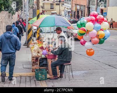 Zacatecas, Mexiko. Dezember. 2009. Straßenverkäufer verkaufen Obst und farbige Ballons an einer Straßenecke, Menschen gehen auf dem Bürgersteig Stockfoto