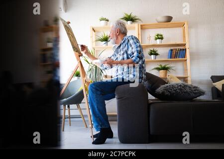 Glücklich Rentner Mann Malerei auf Leinwand für Spaß zu Hause Stockfoto
