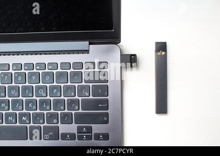 MOSKAU - 26. Juni 2020: Juul e-Zigarette Nikotindampfstab und Laptop mit usb-Ladegerät Stockfoto