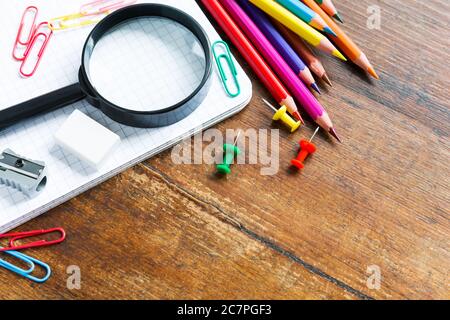 Zurück zur Schule: Notizbuch, Bleistifte, Lupe auf Holztisch Stockfoto