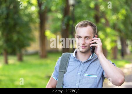 Junger Mann im Park mit einem Smartphone Stockfoto