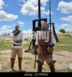 LES BAUX, FRANKREICH - JUL 9, 2014: Amateur historische Rekonstruktion der mittelalterlichen Kriege. Männer als mittelalterliche Krieger gekleidet stehen in der Nähe des Katapult. Les Bau Stockfoto