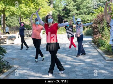 Eine Gruppe von chinesisch-amerikanischen Frauen, die Masken tragen und Distanzierungen beobachten, üben modernen chinesischen Tanz. In Flushing, Queens, New York City Stockfoto