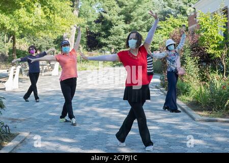 Eine Gruppe von chinesisch-amerikanischen Frauen, die Masken tragen und Distanzierungen beobachten, üben modernen chinesischen Tanz. In Flushing, Queens, New York City Stockfoto