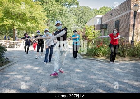 Eine Gruppe von chinesisch-amerikanischen Frauen, die Masken tragen und Distanzierungen beobachten, üben modernen chinesischen Tanz. In Flushing, Queens, New York City Stockfoto