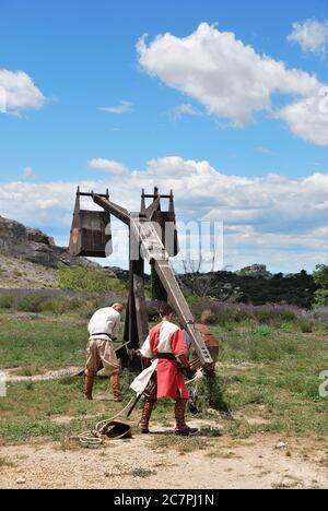 LES BAUX, FRANKREICH - JUL 9, 2014: Amateur historische Rekonstruktion der mittelalterlichen Kriege. Herren als mittelalterlicher Krieger verkleidet laden das Katapult für Feuer. Les Stockfoto