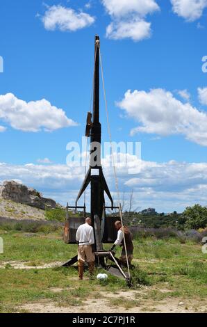 LES BAUX, FRANKREICH - JUL 9, 2014: Amateur historische Rekonstruktion der mittelalterlichen Kriege. Herren als mittelalterlicher Krieger verkleidet laden das Katapult für Feuer. Les Stockfoto