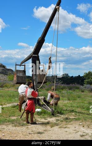 LES BAUX, FRANKREICH - JUL 9, 2014: Amateur historische Rekonstruktion der mittelalterlichen Kriege. Herren als mittelalterlicher Krieger verkleidet laden das Katapult für Feuer. Les Stockfoto