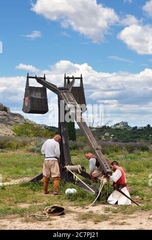 LES BAUX, FRANKREICH - JUL 9, 2014: Amateur historische Rekonstruktion der mittelalterlichen Kriege. Herren als mittelalterlicher Krieger verkleidet laden das Katapult für Feuer. Les Stockfoto