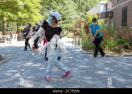 Eine Gruppe von chinesisch-amerikanischen Frauen, die Masken tragen und Distanzierungen beobachten, üben modernen chinesischen Tanz. In Flushing, Queens, New York City Stockfoto