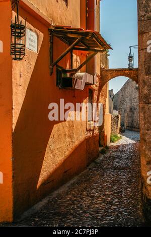 Enge Kopfsteinpflasterstraße im alten Stadtzentrum von rodos griechenland. Die Straße hat alte Laternen hängen an den Wänden endet im Hintergrund die Straße e Stockfoto