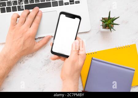 Männliche Hände mit Handy und Laptop auf weißem Hintergrund Stockfoto
