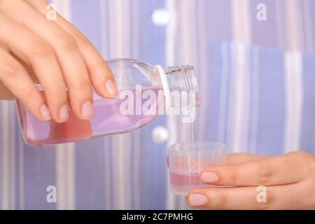 Frau Gießen Hustensirup aus der Flasche in den Becher, Nahaufnahme Stockfoto