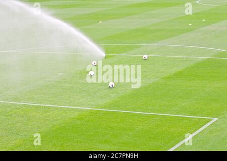 Bewässerungsrasen arbeiten auf dem frischen grünen Gras auf dem Fußballplatz Stockfoto