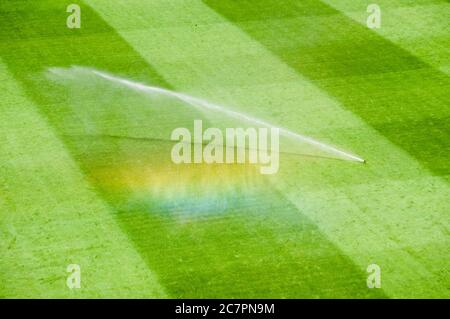 Bewässerungsrasen arbeiten auf dem frischen grünen Gras auf dem Fußballplatz Stockfoto