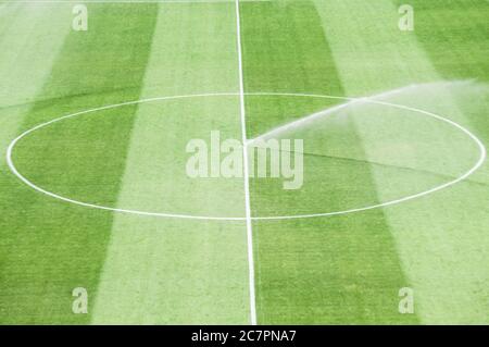 Bewässerungsrasen arbeiten auf dem frischen grünen Gras auf dem Fußballplatz Stockfoto