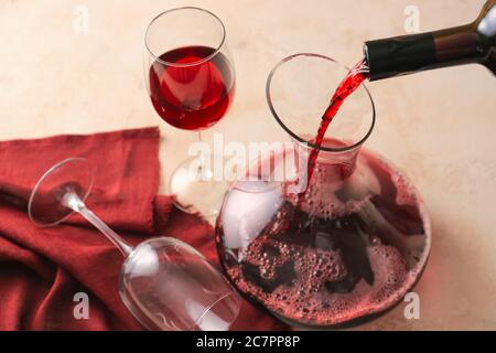 Gießen von Wein aus der Flasche in den Dekanter auf dem Tisch Stockfoto