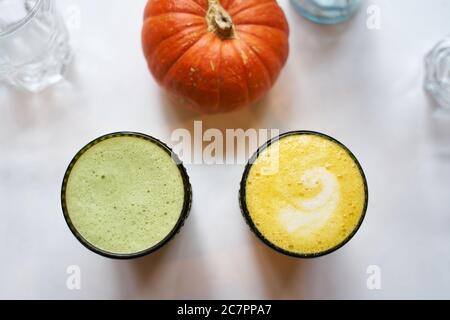 Gesundes Getränk Kurkuma und Ingwer gelbe Latte mit Kokosmilch und vegane Matcha Latte mit grünem Tee und Hafermilch, Draufsicht, weißer Hintergrund Stockfoto