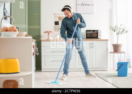 Schöner junger Mann, der in der Küche Boden wischt Stockfoto
