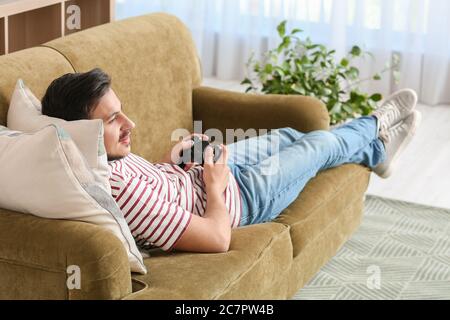 Schöner junger Mann spielt Videospiel zu Hause Stockfoto