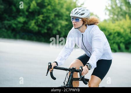 Junge sportliche Frau, die auf einem Profi-Fahrrad in einem weißen Helm Stockfoto