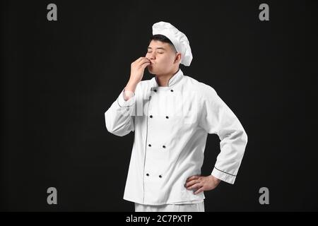 Schöner asiatischer Koch auf dunklem Hintergrund Stockfoto