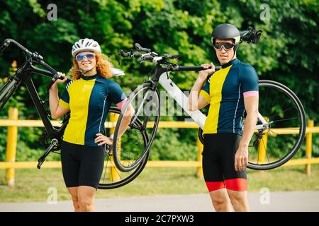 Athletisches Paar posiert mit Fahrrädern auf den Schultern, trägt die gleichen Farben Stockfoto