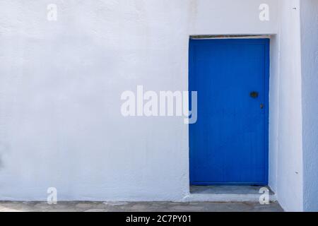 Blaue Farbe bemalte Holztür auf einer weißen Wand, griechische Insel Architektur, Kopie Raum. Feiertage in Griechenland Kartenvorlage Stockfoto