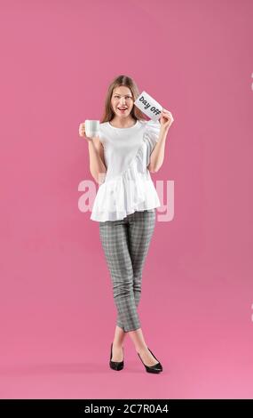 Glückliche Geschäftsfrau mit Tasse Tee und Papier Blatt mit Text TAG FREI auf farbigem Hintergrund. Konzept des Wochenendes Stockfoto