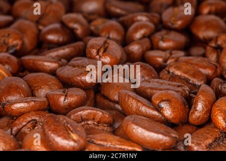 Nahaufnahme von gerösteten Kaffeebohnen, die auf einer Tischplatte verteilt sind Stockfoto