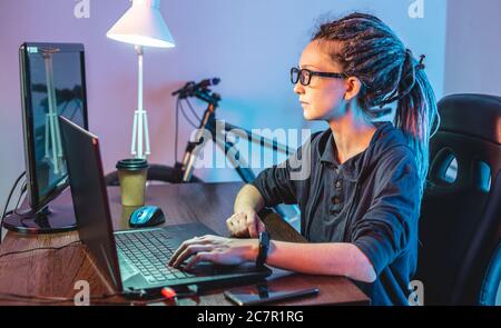Moderne junge weibliche Programmierer ist das Schreiben von Programmcode auf einem Laptop zu Hause. Remote-Arbeit im IT-Bereich. Das Konzept der Softwareentwicklung. Stockfoto