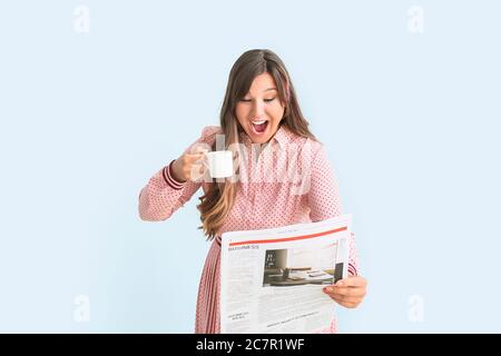 Glückliche Frau mit Zeitung trinken heißen Kaffee auf farbigem Hintergrund Stockfoto