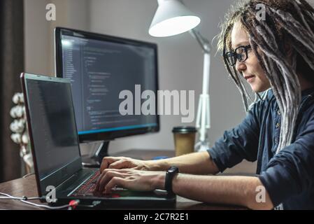 Moderne junge weibliche Programmierer ist das Schreiben von Programmcode auf einem Laptop zu Hause. Remote-Arbeit im IT-Bereich. Das Konzept der Softwareentwicklung. Stockfoto