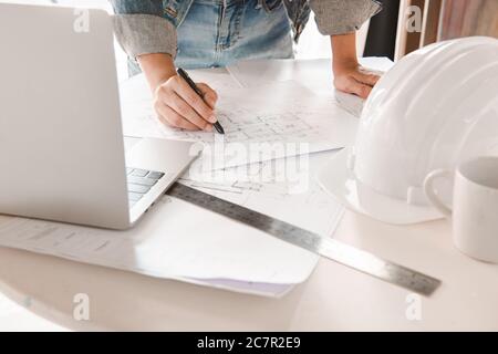 Ingenieure halten einen Stift, der auf ein Gebäude zeigt, und planen mit einem Laptop den Projektplan. Engineering und Baukonzept. Stockfoto