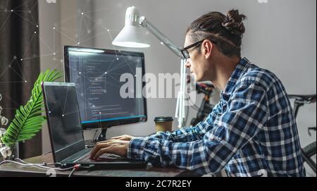 Männlicher Programmierer schreibt Programmcode auf einem Laptop zu Hause. Remote-Arbeit im IT-Bereich. Das Konzept der Softwareentwicklung. Stockfoto