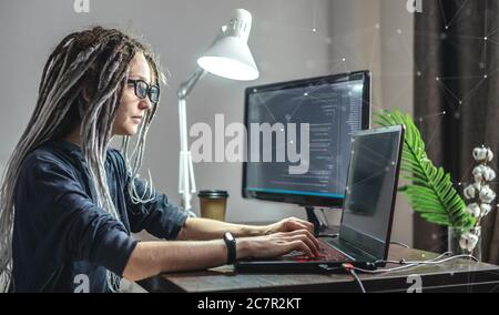 Moderne junge weibliche Programmierer ist das Schreiben von Programmcode auf einem Laptop zu Hause. Remote-Arbeit im IT-Bereich. Das Konzept der Softwareentwicklung. Stockfoto