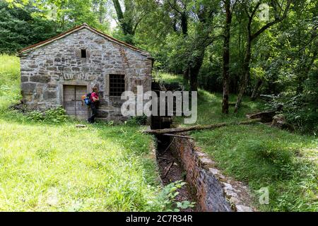Frau, die vor der alten Mühle steht, Wassermühle, Stockfoto