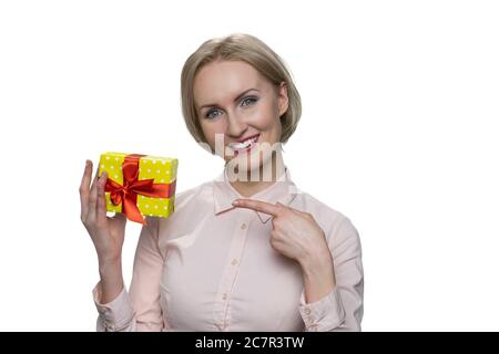 Glücklich lächelnde blonde Frau poiting auf Geschenk in ihrer Hand. Stockfoto