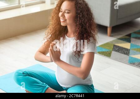 Junge schwangere Yoga zu Hause Stockfoto