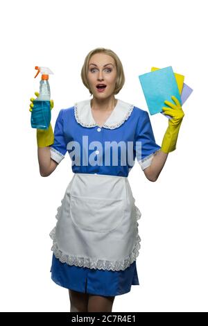 Überrascht Zimmermädchen mit offenem Mund halten Reiniger Spray und Schwammtücher auf weißem Hintergrund. Stockfoto