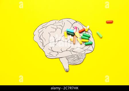Menschliches Gehirn und Pillen auf farbigem Hintergrund. Konzept der Demenz Stockfoto