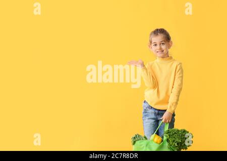 Kleines Mädchen mit Essen in Tasche auf farbigem Hintergrund Stockfoto