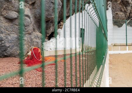 Unbesetztes altes Höhlenhaus mit weißer Wand und eingezäunt, um es als historisches Merkmal in Playa San Juan, Teneriffa, Kanarische Insel zu erhalten Stockfoto